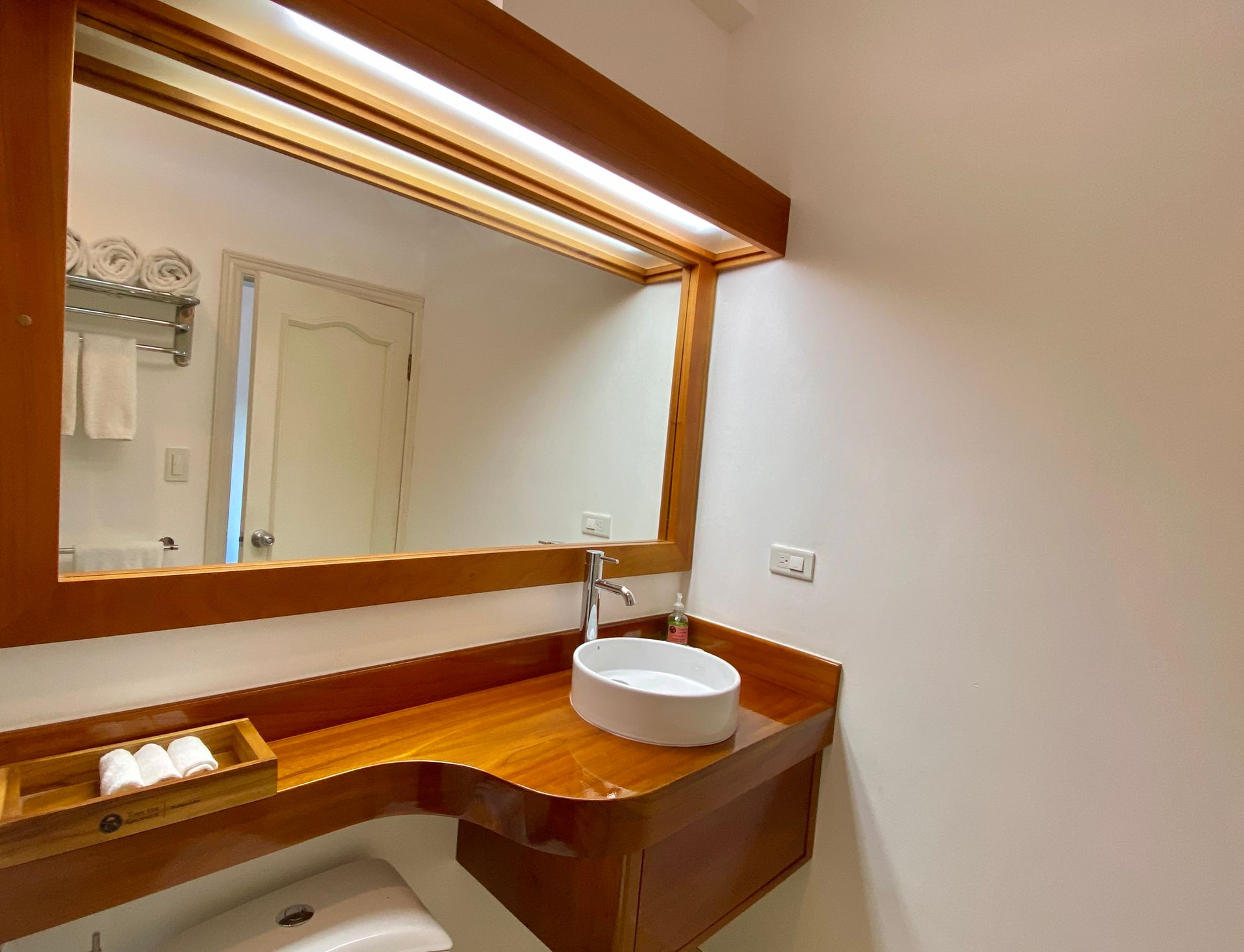 A Galapagos hotel Bathroom vanity with wooden counter, large mirror, and white vessel sink in a bright room.