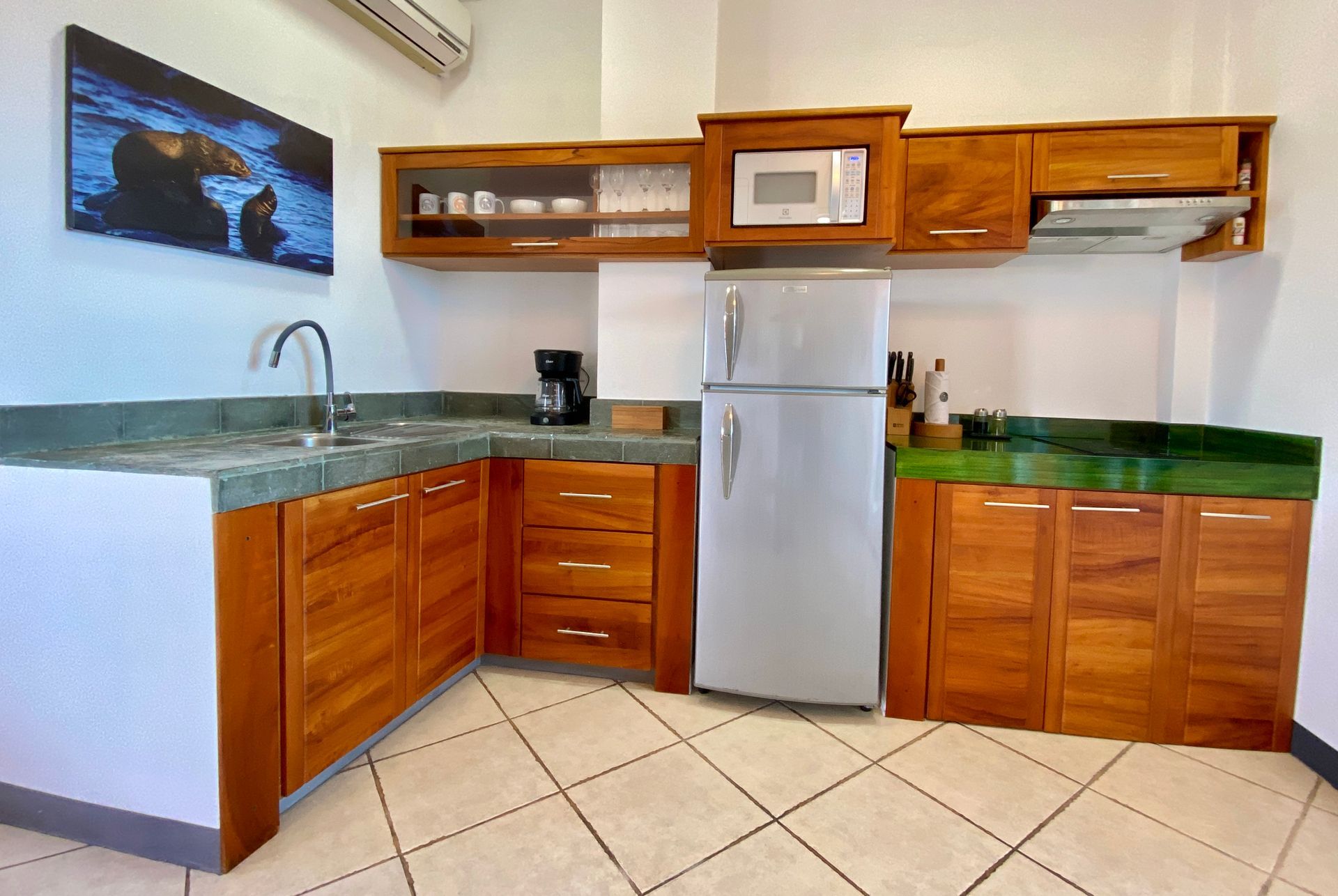 In a Galapagos Hotel a Modern kitchen with wooden cabinets, green countertops, stainless fridge, and tiled floor