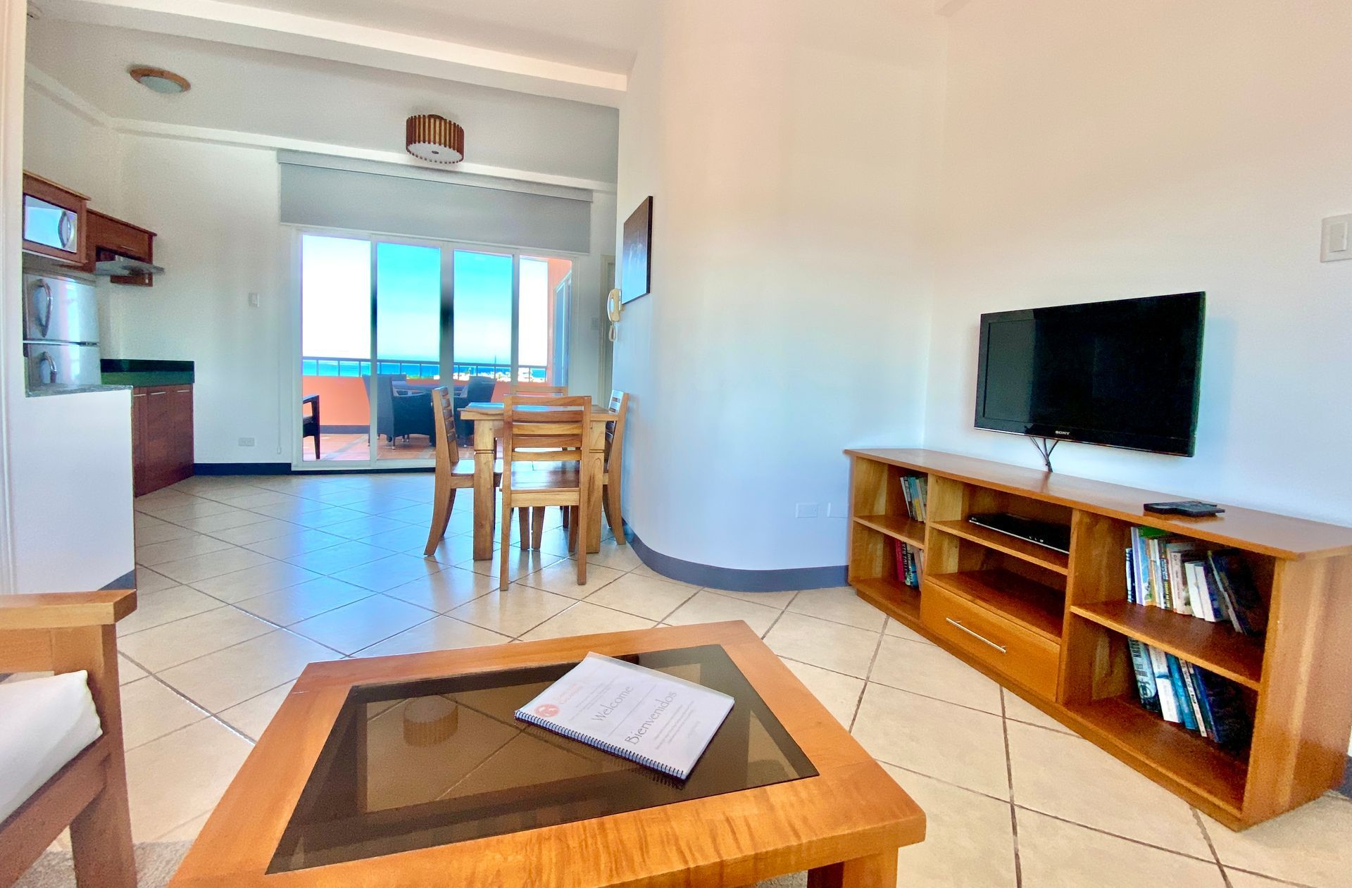 Bright Galapagos hotel room with TV, wooden stand, coffee table, and dining area in the background