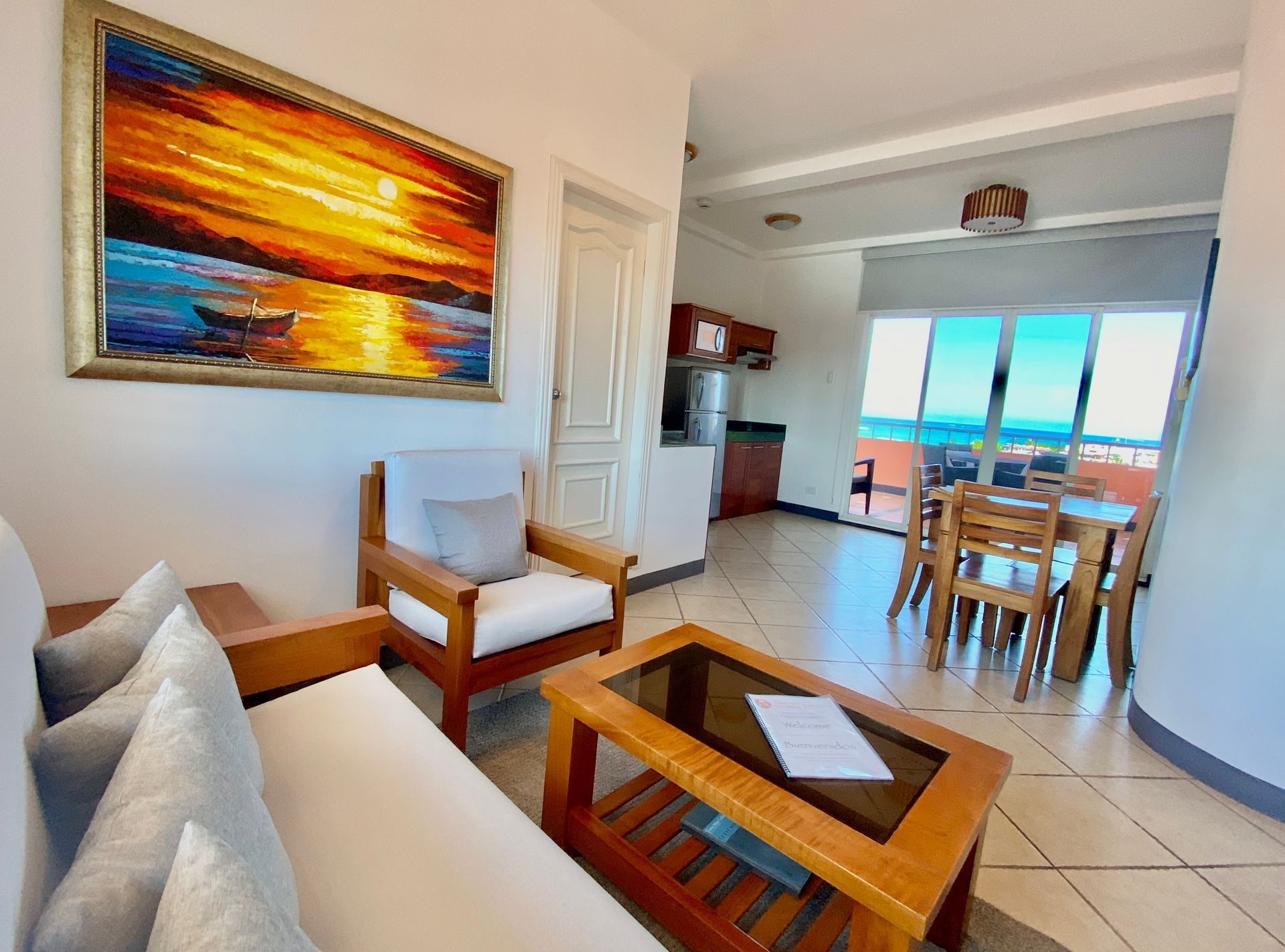 Bright Galapagos Hotel living room with sofa, armchair, coffee table, and ocean view through dining area windows