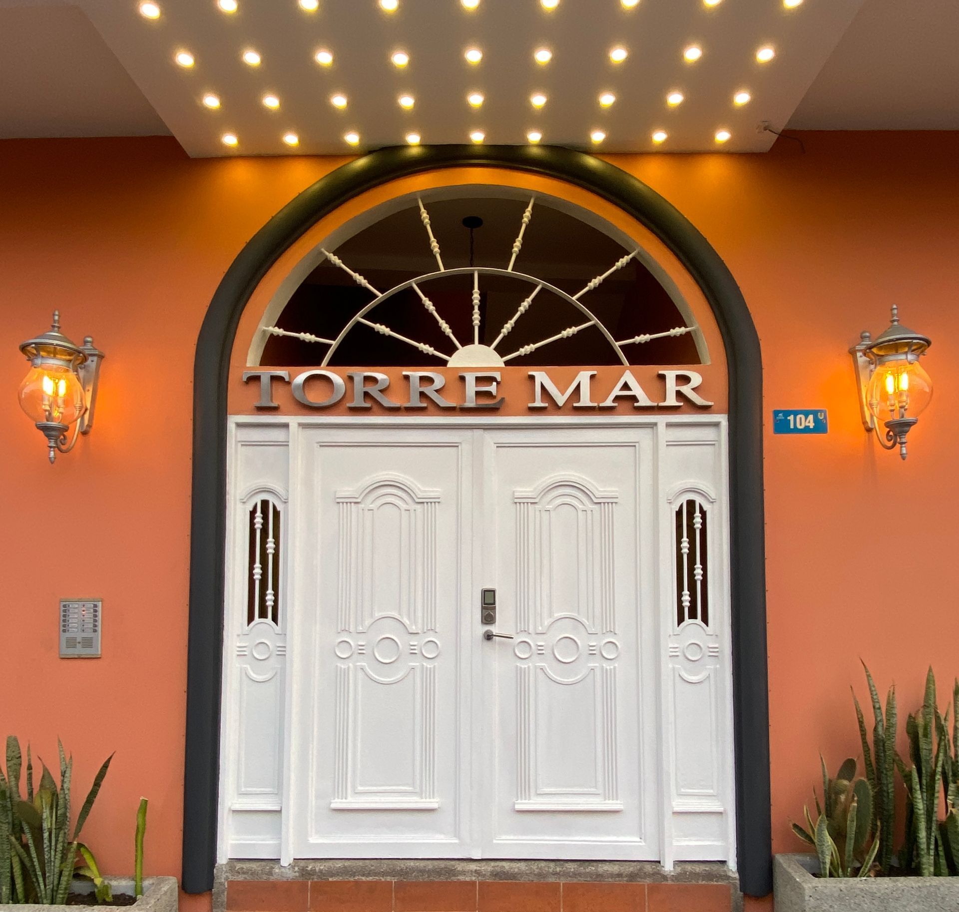 Orange hotel entrance with white double doors, arched window, and “TORRE MAR” sign above in the Galapagos Islands.