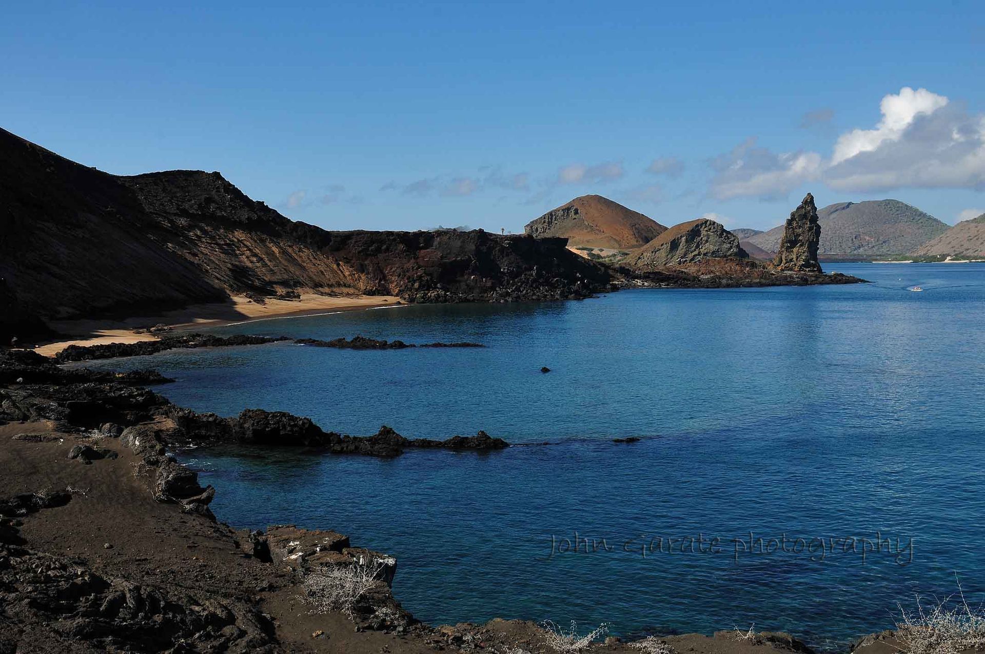 Rocky coastline with black volcanic cliffs and blue ocean under a clear sky in Galapagos