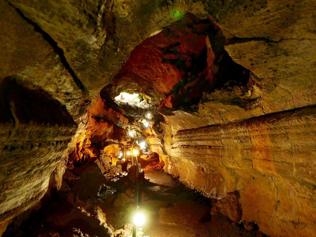 Lit lava tunnel passage with warm light reflecting off rocky walls in Galapagos