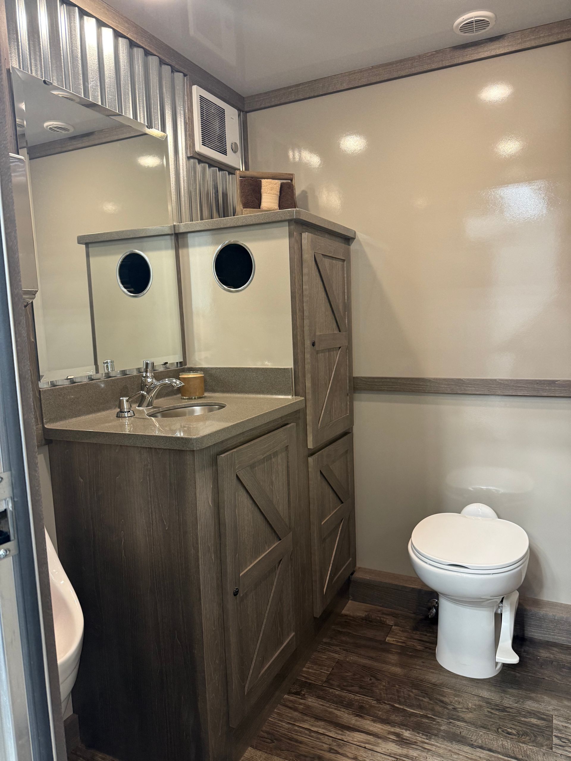 A rustic-style bathroom with a wooden vanity, corrugated metal accents, a mirror, and a white toilet.