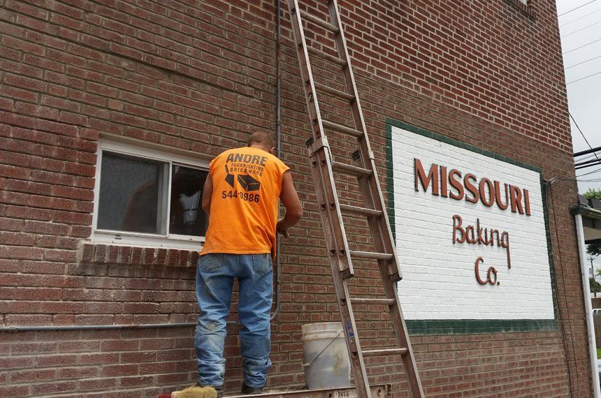 Worker on ladder beside brick building with Missouri Ruling Co. sign