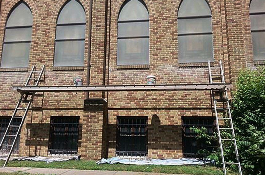 Brick building with arched windows and scaffolding along the lower façade.