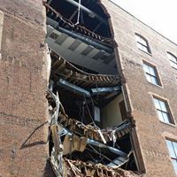 Damaged brick apartment building with collapsed balconies and exposed floors