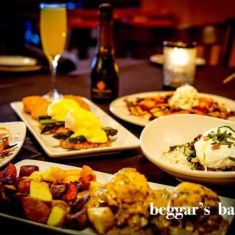 Multiple breakfast and brunch plates, a mimosa, and a bottle of bubbly are arranged on a table at Beggar's Banquet.