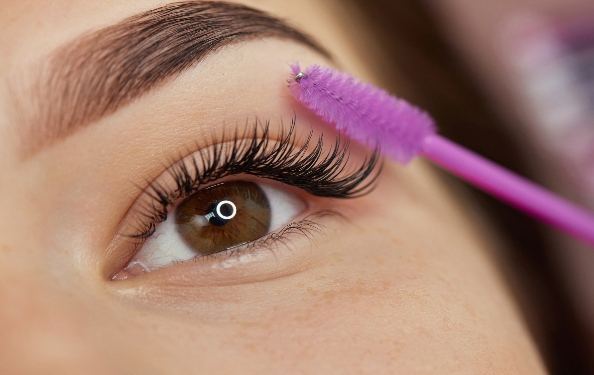 Close-up of an eye with mascara being applied by a pink mascara wand