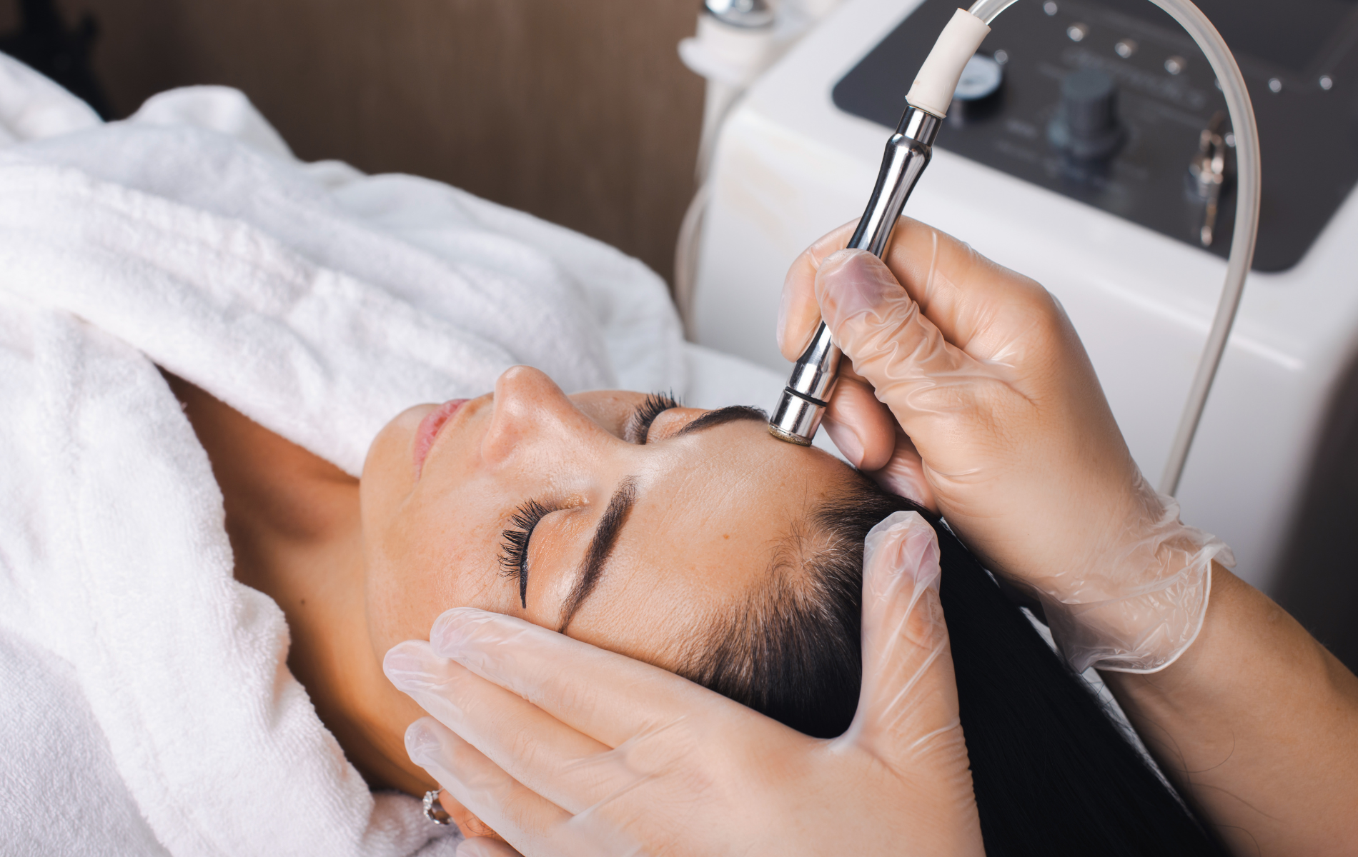 Cosmetic facial treatment with a handheld device on a woman’s face in a spa setting