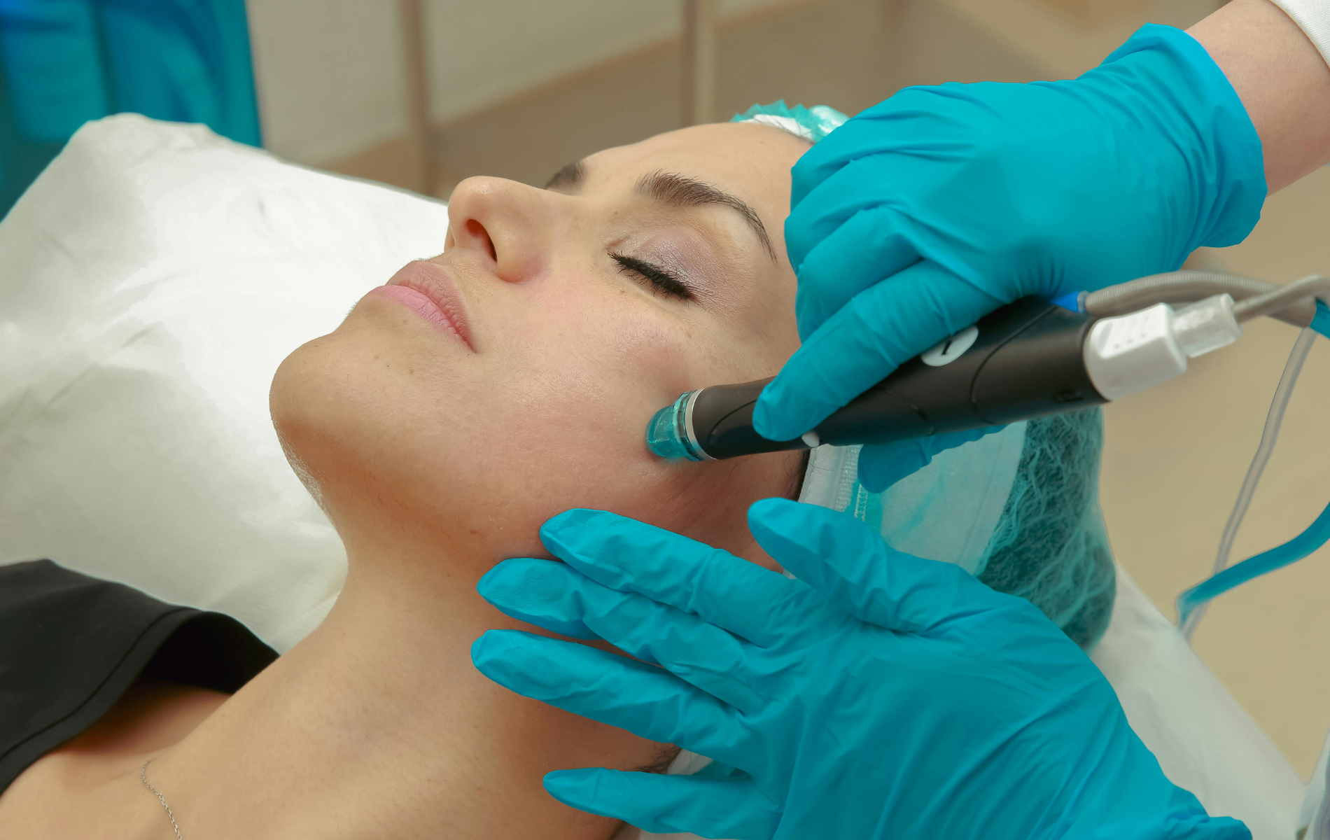 Gloved clinician applying a facial treatment with a handheld device to a reclining patient