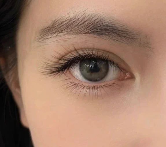 Close-up of a brown eye with long eyelashes and a neatly shaped eyebrow