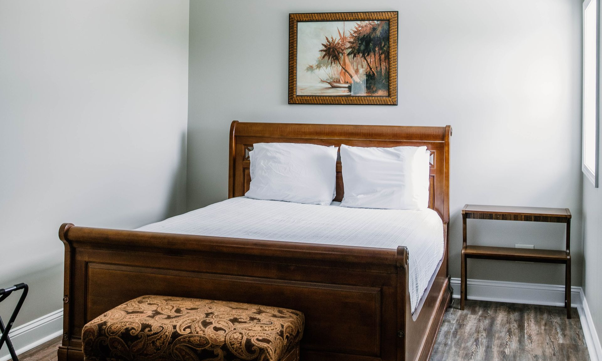Cozy bedroom with a neatly made bed, gray walls, soft natural light, and a window beside the bed