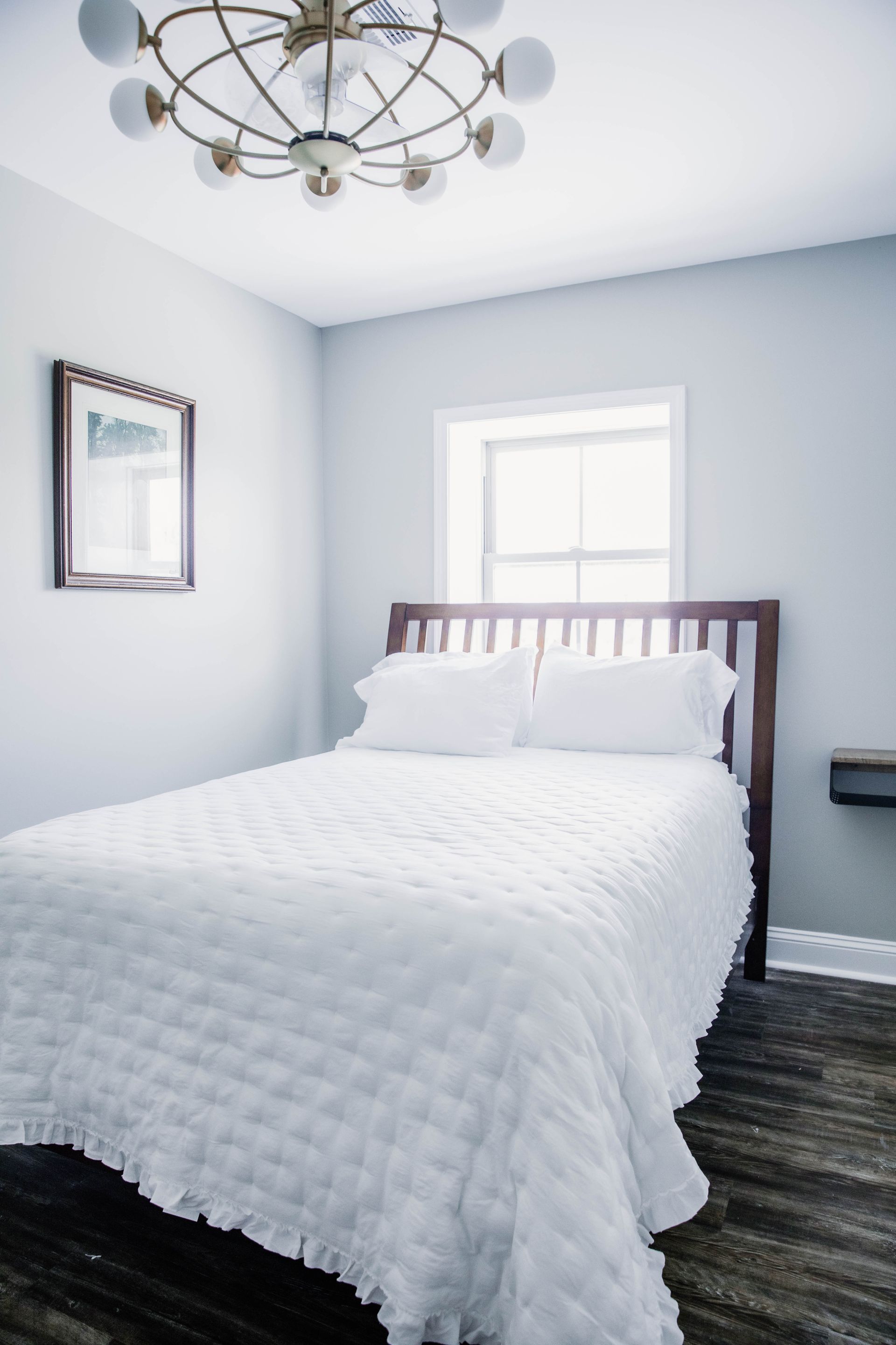 White bed with pillows beside beige curtains in a softly lit modern bedroom