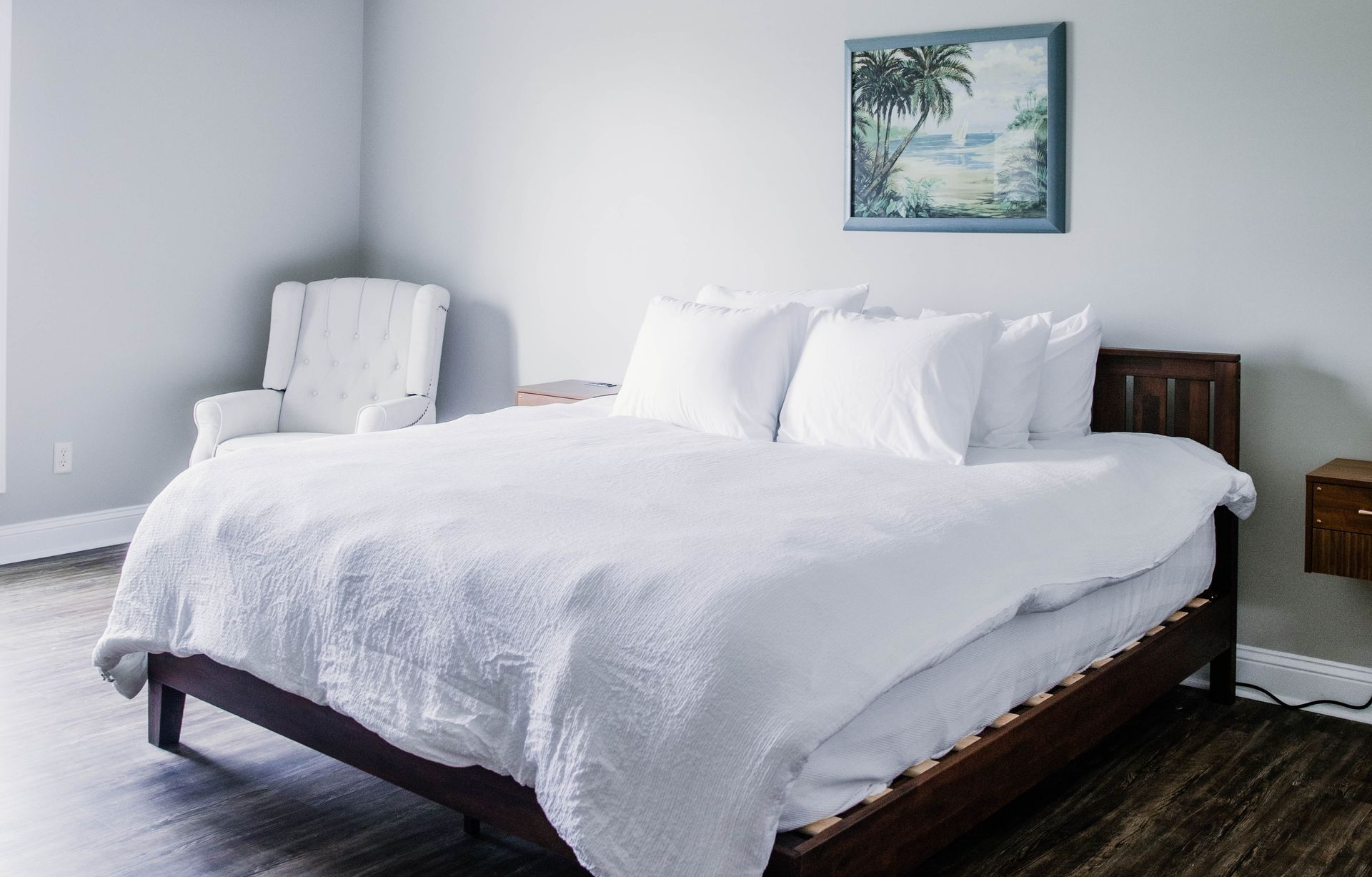Neatly made bed with white linens, beige headboard, decorative pillows, and a book on the blanket