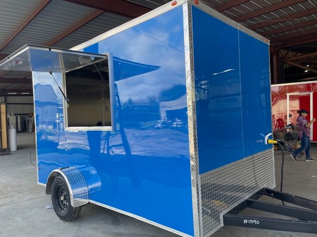 Blue food trailer with serving window open. Black wheels, diamond plate trim, in workshop.