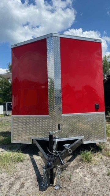 Red and silver enclosed cargo trailer, set outside.
