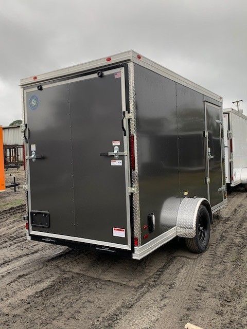 Dark gray cargo trailer on muddy ground.
