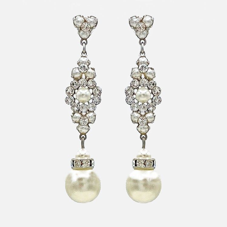 A pair of earrings with pearls and rhinestones on a white background.
