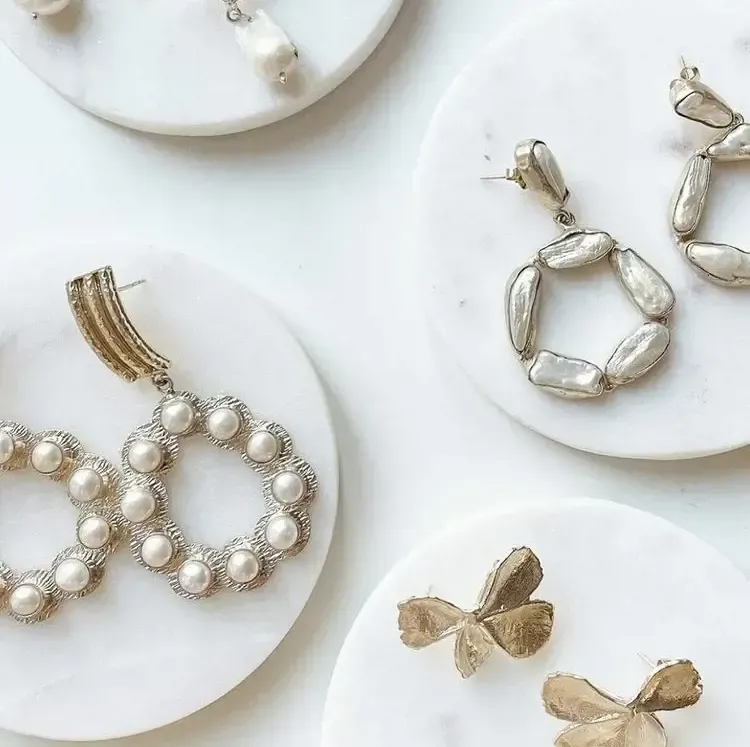 A variety of earrings are displayed on white plates
