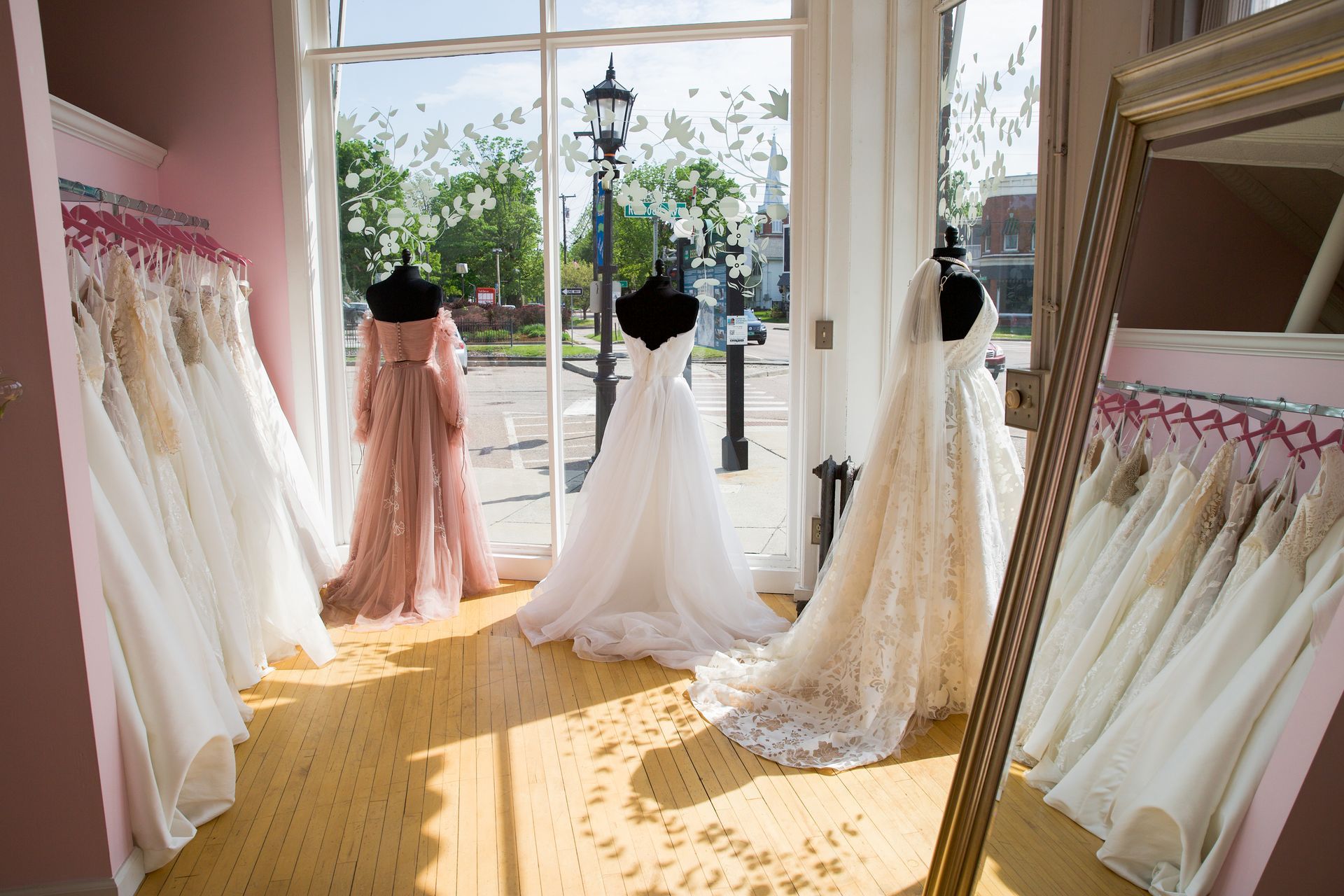 A room filled with lots of wedding dresses and a mirror.