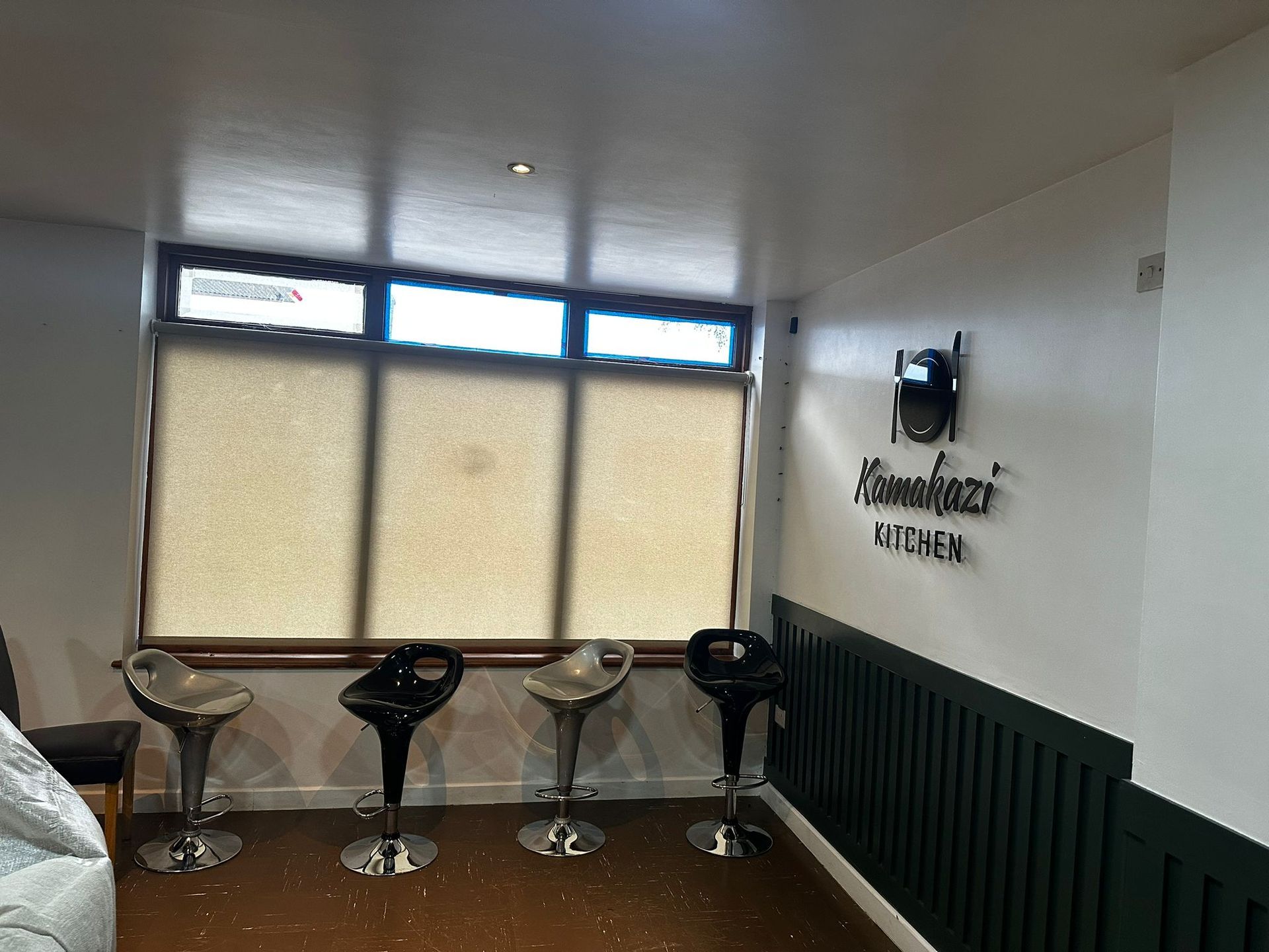 A room with three bar stools in front of a window.