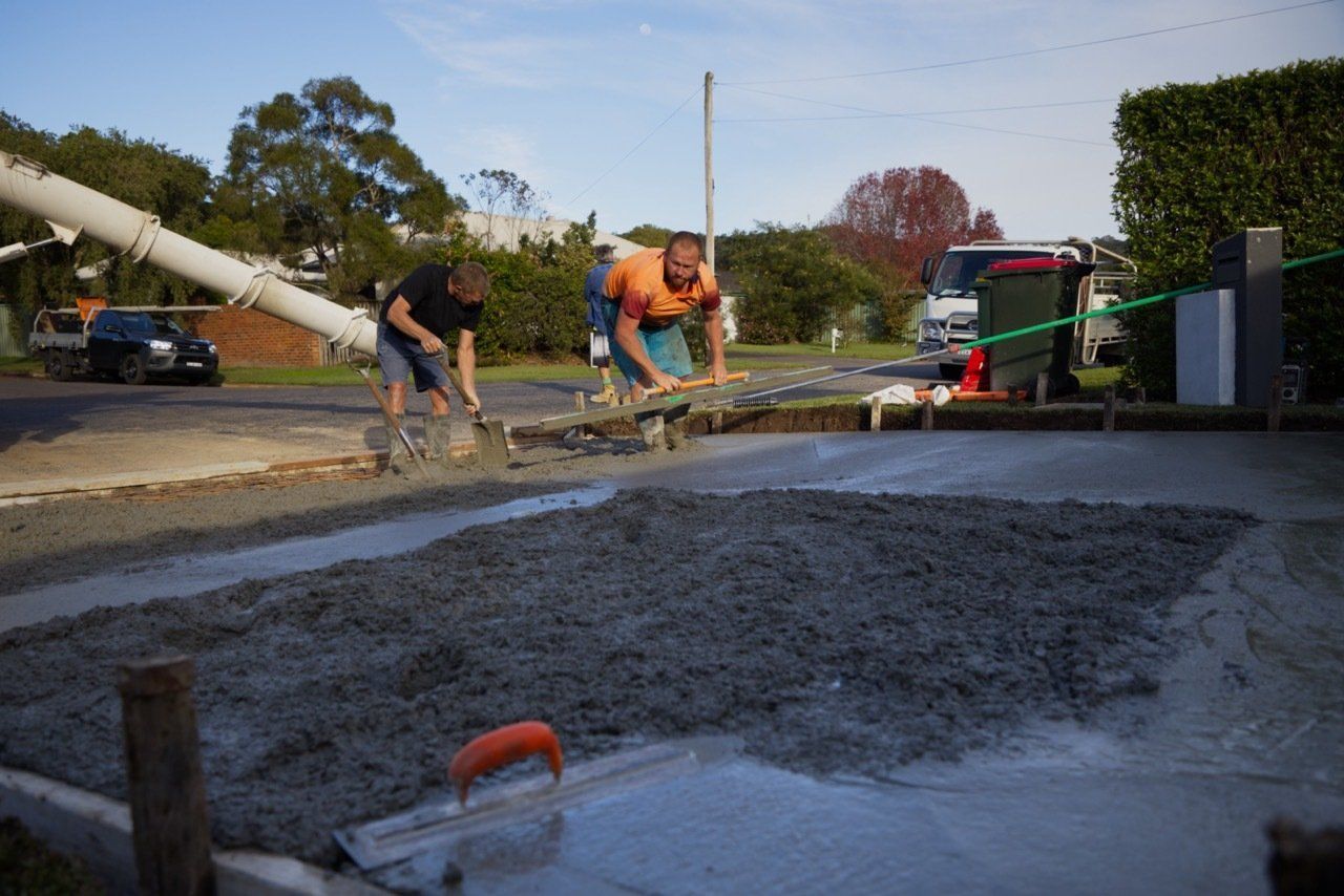 Two Workers Spreading Fresh Concrete on a Driveway — Easy Mix Concrete in Berkeley Vale, NSW