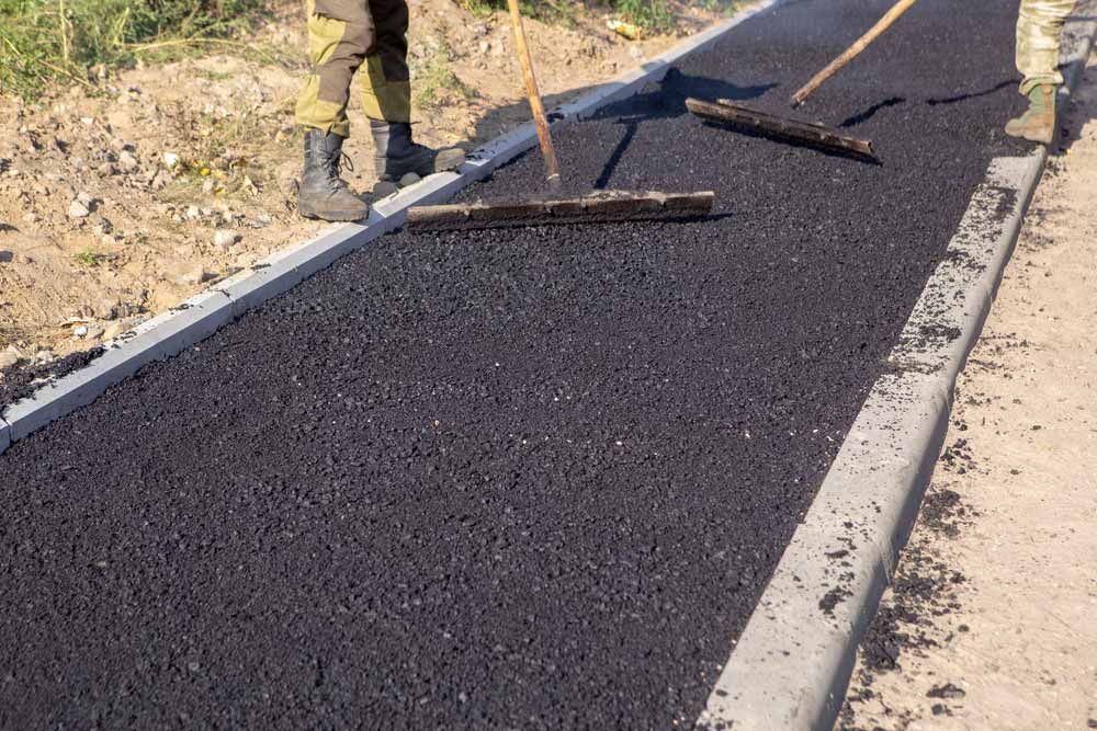 Workers Paving a Road With Fresh, Dark Asphalt — Easy Mix Concrete In Woy Woy, NSW