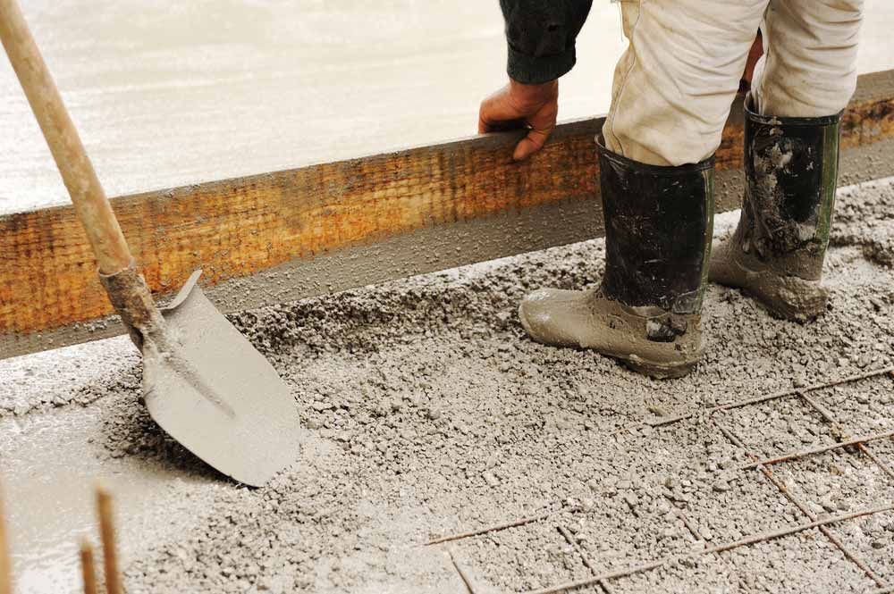 Person in Boots Leveling Wet Concrete With a Shovel — Easy Mix Concrete In Gosford, NSW