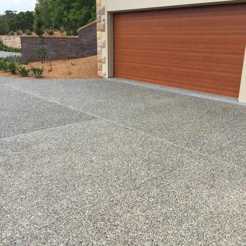 Exposed Aggregate Driveway in Front of a Brown Garage Door — Easy Mix Concrete In Berkeley Vale, NSW