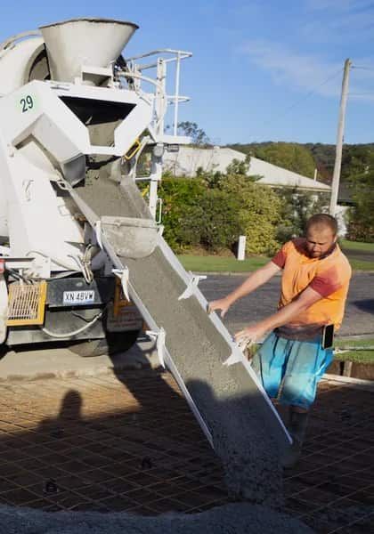 Man In Orange Shirt Guides Concrete From A Truck Chute — Easy Mix Concrete In Berkeley Vale, NSW