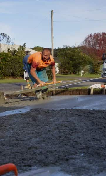 Man Leveling Concrete With a Tool Outdoors — Easy Mix Concrete In Berkeley Vale, NSW