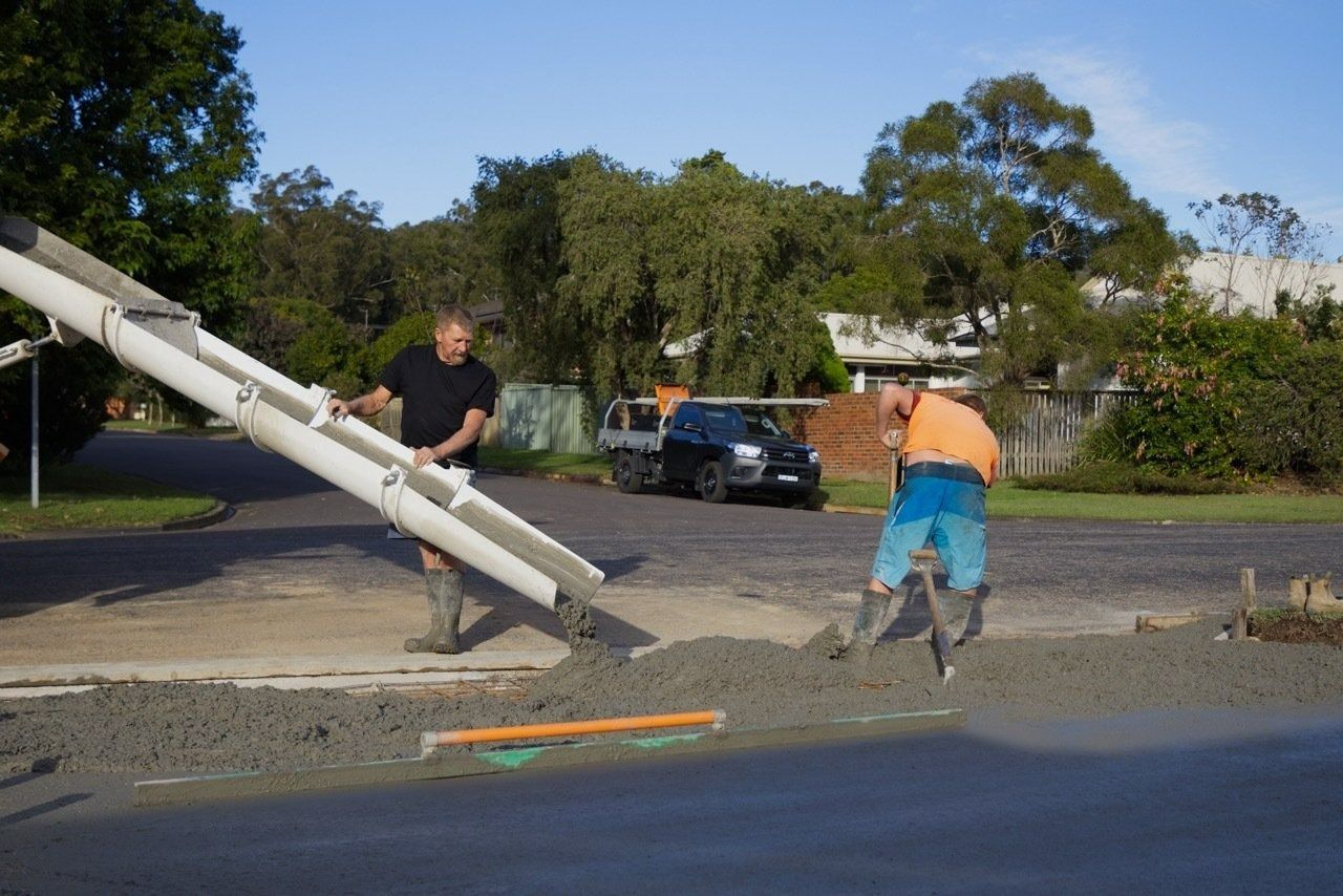 Two Workers Pouring Concrete on a Street With a Concrete Pump — Easy Mix Concrete in Berkeley Vale, NSW