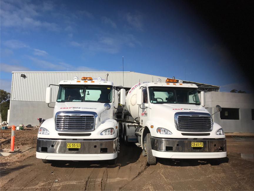 Two White Cement Trucks Parked in Front of a Building — Easy Mix Concrete in Berkeley Vale, NSW