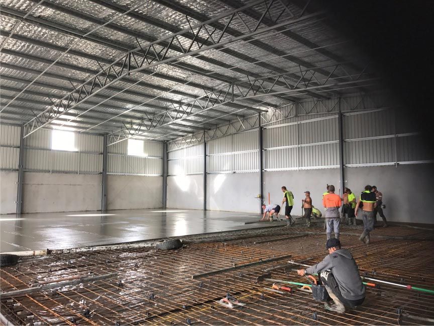 Workers Pouring Concrete in a Large, Open Metal Building — Easy Mix Concrete in Berkeley Vale, NSW