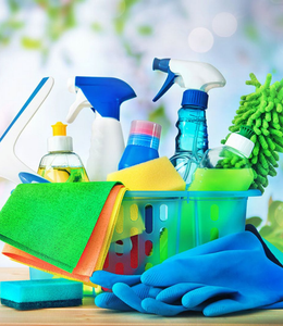 Cleaning supplies and colorful sponges in a basket, with spray bottles and a scrub brush.