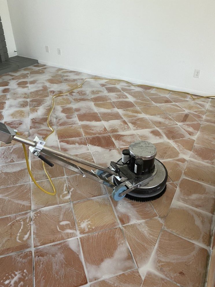 Floor buffing machine cleaning a tiled room with white residue on the floor