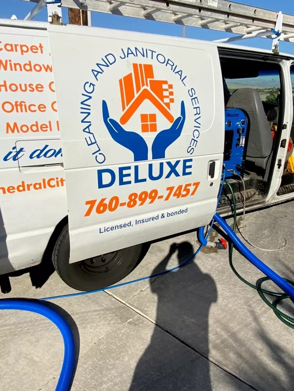 White cleaning service van with blue hose and orange/blue logo, parked outside a building