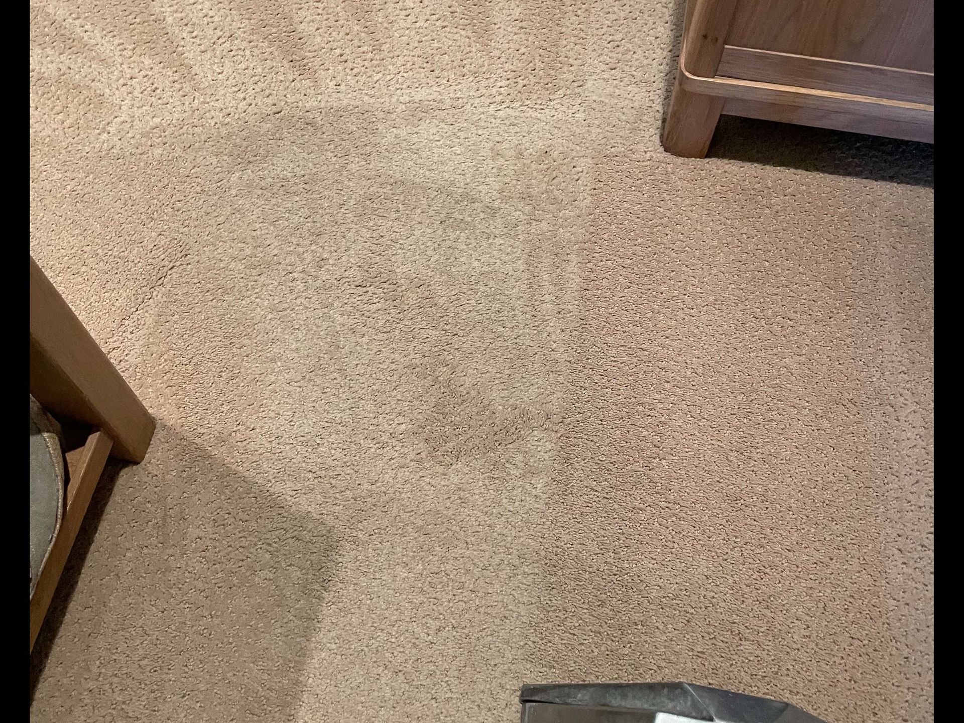 Carpeted floor with the corner of a wooden chair and a dresser visible at the edges.