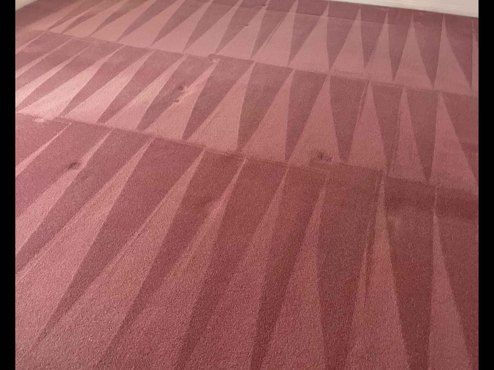 Pink patterned carpet with geometric triangular designs in a hallway or room.