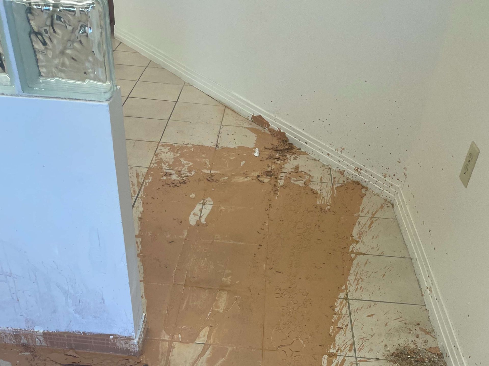 Damaged floor tiles and peeled linoleum in a corner near a wall and doorway