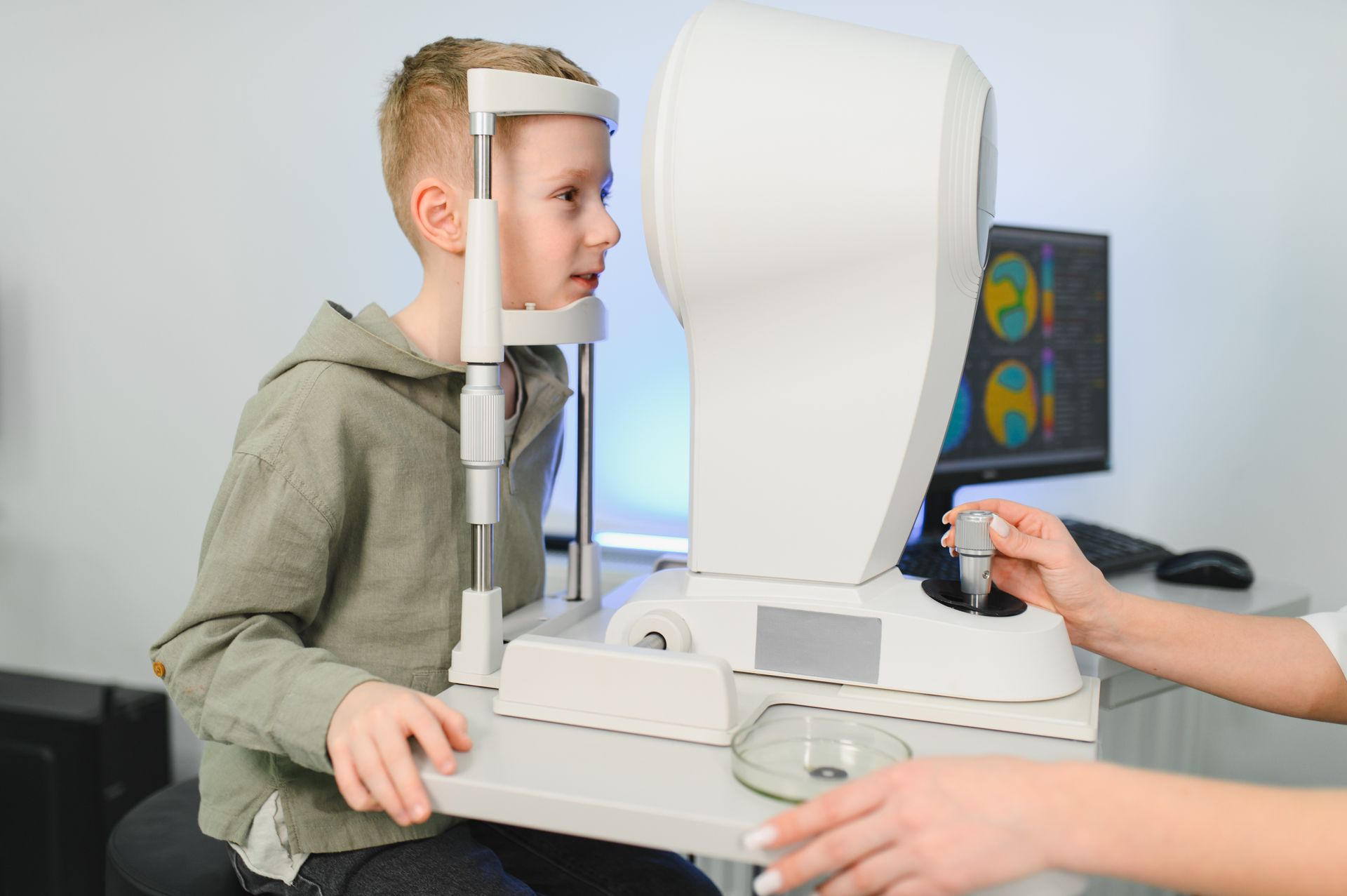 Child having eye exam with corneal topographer at pediatric ophthalmologist's clinic office. Child having eye exam with corneal topographer at pediatric ophthalmologist's clinic office.