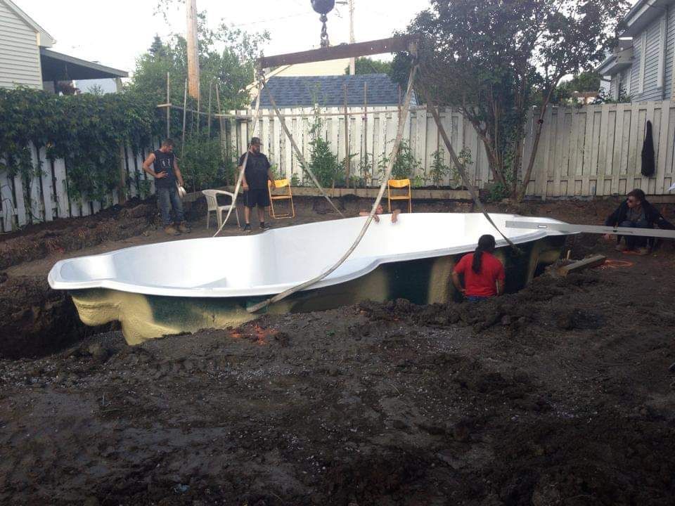 Une grande piscine blanche est soulevée par une grue