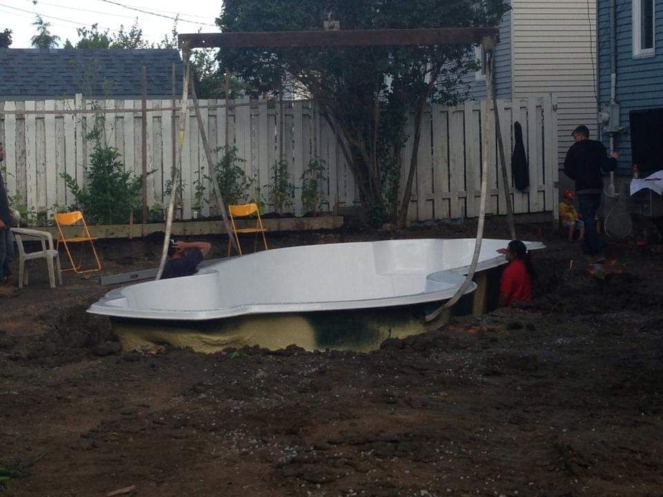 Une grande piscine blanche est en construction dans une cour