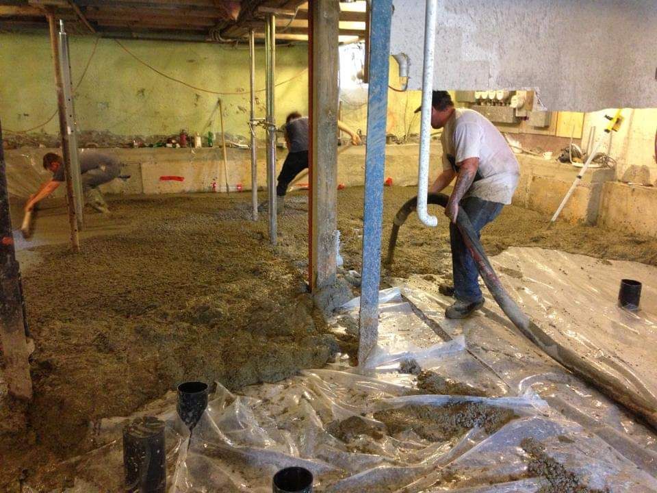 Un groupe d'hommes travaillent sur un sol en béton.
