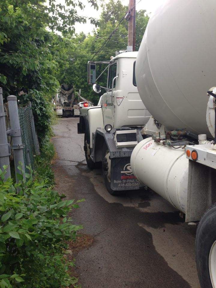 Deux camions sont garés au bord d'une route à côté d'une clôture.