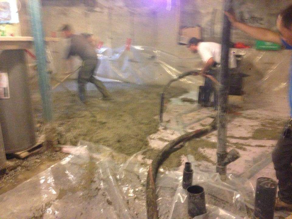 Un groupe de personnes travaillent sur un sol en béton dans un sous-sol.