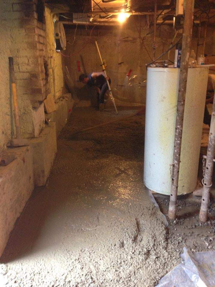 Un homme travaille dans un sous-sol à côté d'un chauffe-eau.