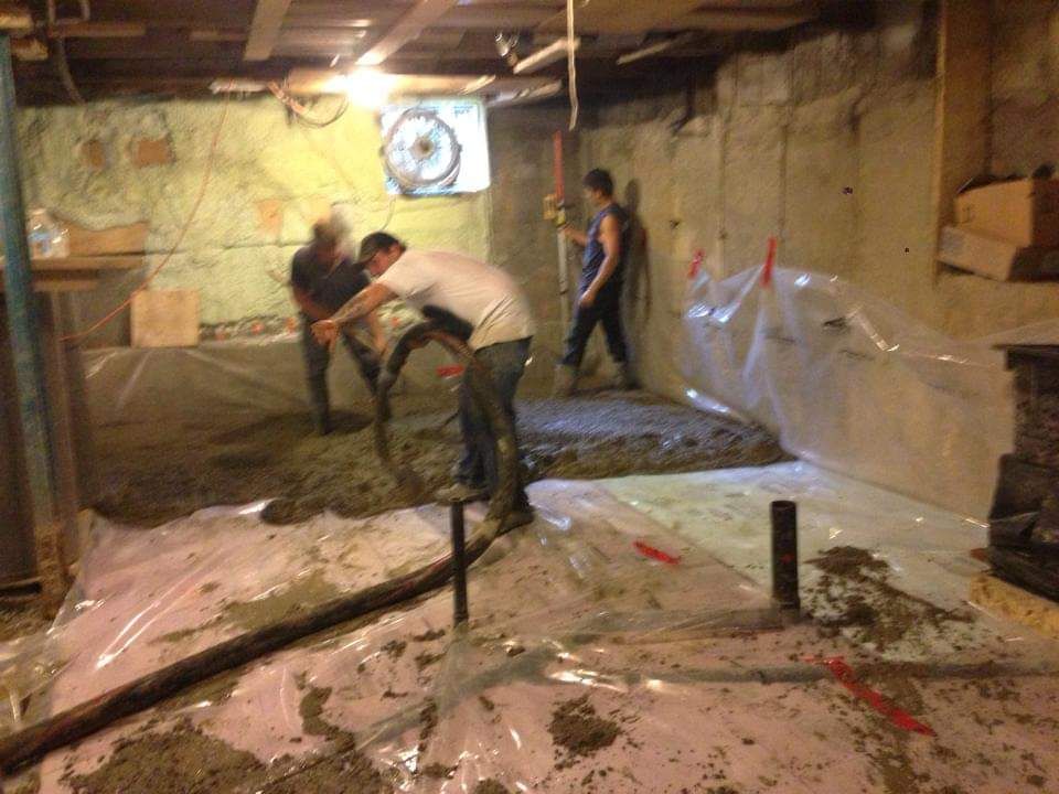 Un groupe de personnes travaillent sur un sol en béton dans un sous-sol.