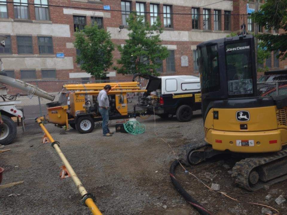 Un homme se tient à côté d’une excavatrice John Deere dans un parking